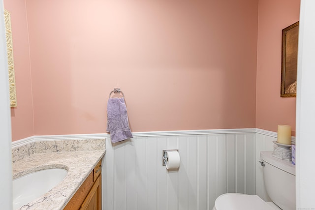 bathroom with a wainscoted wall, vanity, and toilet