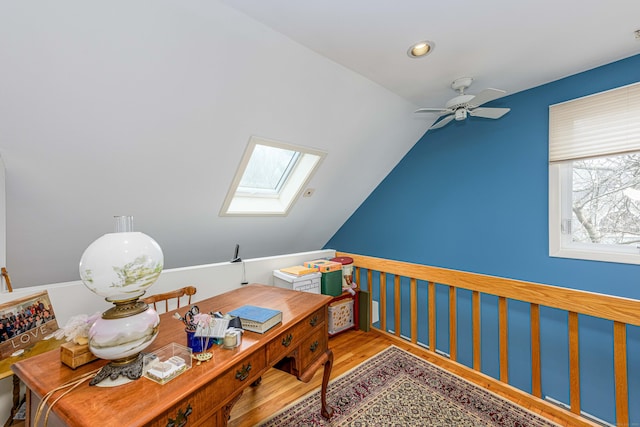 office space featuring lofted ceiling with skylight, a ceiling fan, and wood finished floors