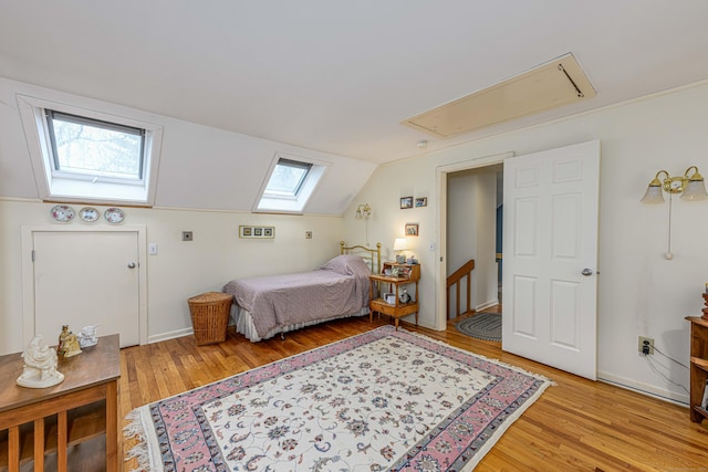 bedroom with light wood-style flooring, attic access, vaulted ceiling, and baseboards