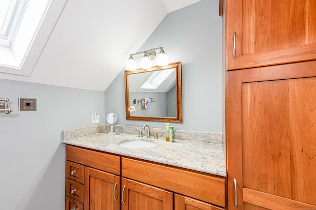 bathroom featuring vaulted ceiling with skylight and vanity