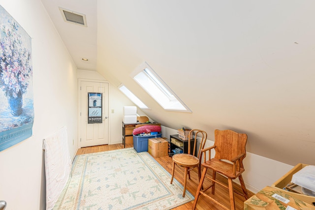 bonus room with lofted ceiling with skylight, light wood-style flooring, and visible vents