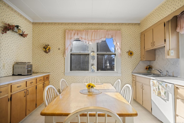 kitchen with light countertops, white dishwasher, a sink, and wallpapered walls