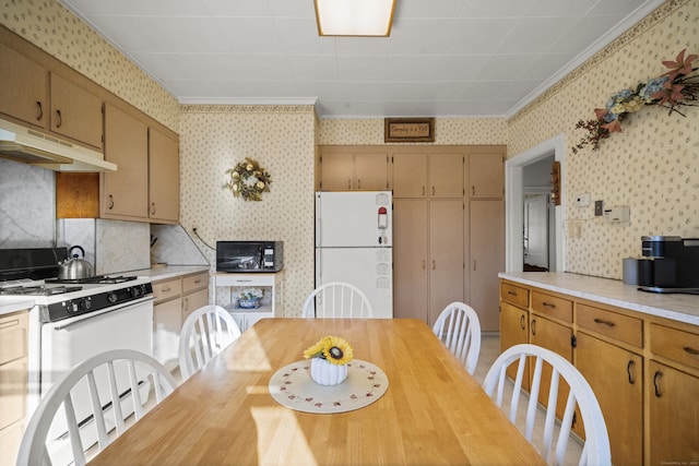 kitchen with ornamental molding, under cabinet range hood, white appliances, and wallpapered walls