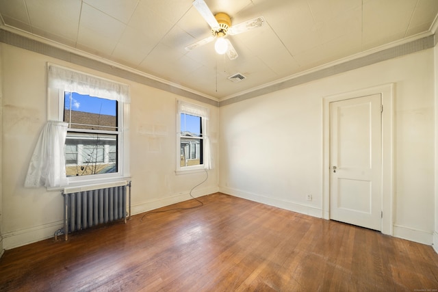 empty room with ornamental molding, radiator, visible vents, and hardwood / wood-style flooring