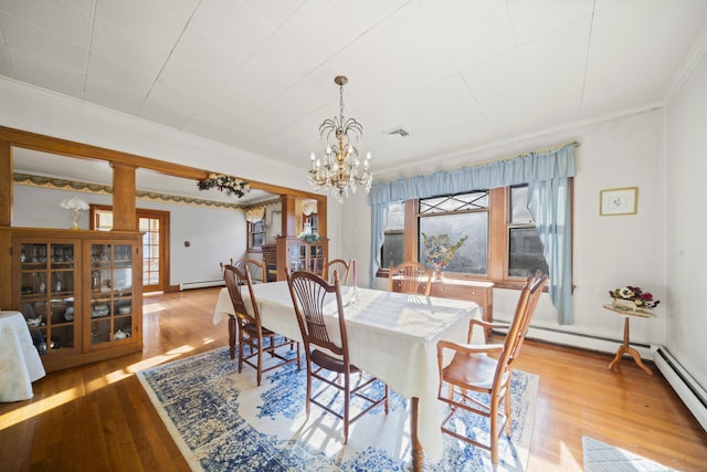 dining area with a baseboard radiator, wood finished floors, visible vents, and crown molding