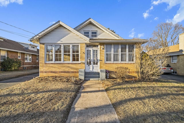 bungalow-style house featuring french doors and brick siding