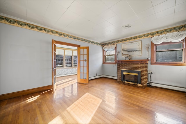 unfurnished living room featuring visible vents, baseboards, wood finished floors, baseboard heating, and a brick fireplace