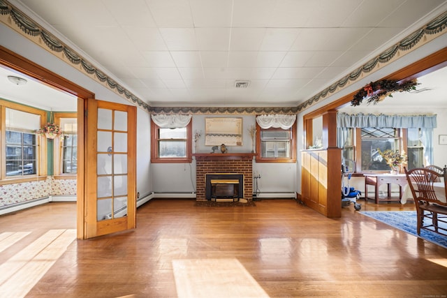 sitting room featuring visible vents, baseboards, a baseboard radiator, wood finished floors, and a brick fireplace