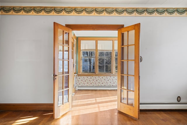 entryway with french doors, a baseboard radiator, wood finished floors, and baseboards