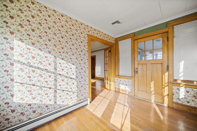 entrance foyer featuring wood-type flooring, visible vents, baseboard heating, ornamental molding, and wallpapered walls