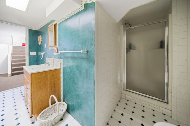 bathroom with a stall shower, vanity, and tile walls