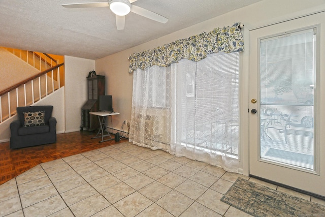 interior space with a ceiling fan, stairway, and a textured ceiling