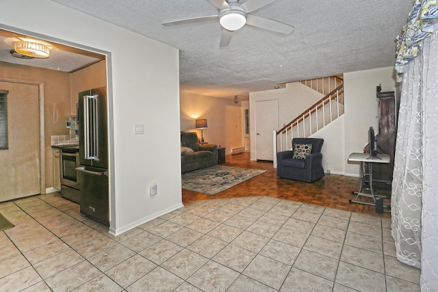 living area with light tile patterned floors, ceiling fan, stairs, and a textured ceiling