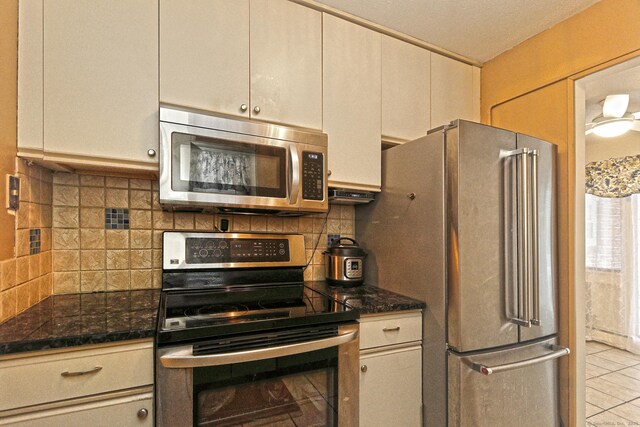 kitchen with stainless steel appliances, cream cabinetry, light tile patterned floors, and tasteful backsplash