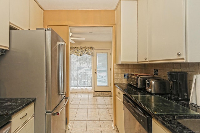 kitchen with a toaster, decorative backsplash, appliances with stainless steel finishes, dark stone countertops, and light tile patterned flooring