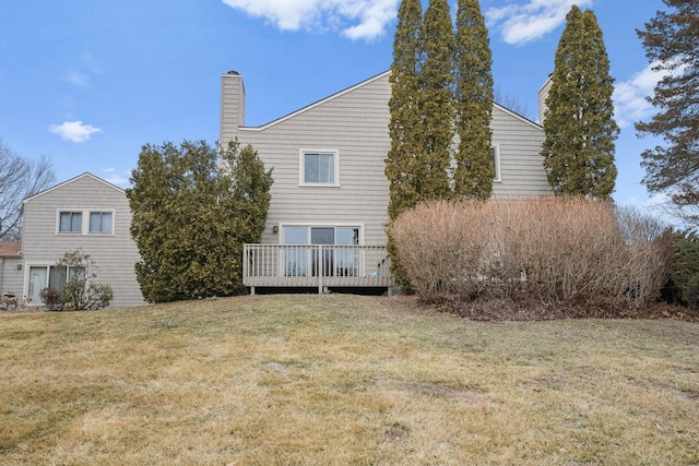 back of property with a chimney, a yard, and a deck