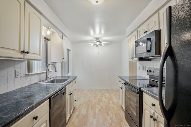 kitchen featuring tasteful backsplash, dark countertops, light wood-style flooring, a sink, and black appliances