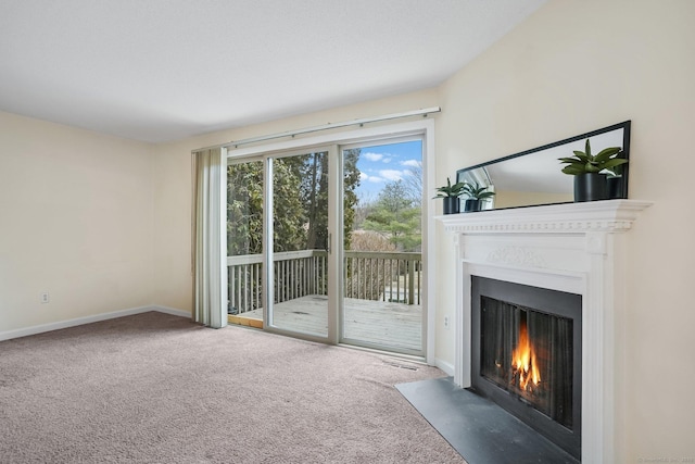 unfurnished living room with a fireplace with flush hearth, carpet flooring, and baseboards