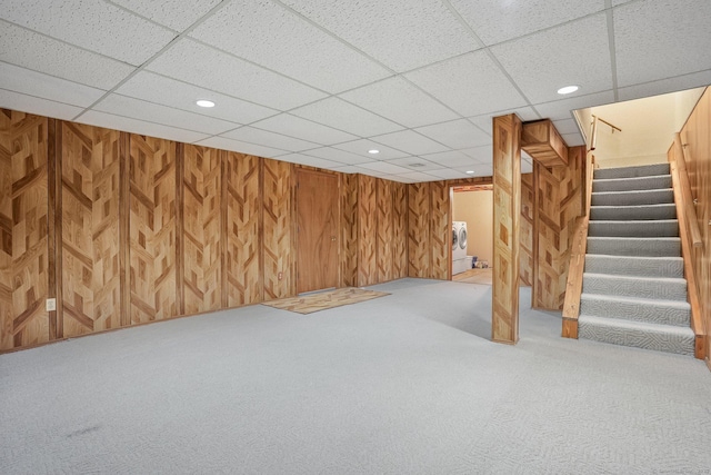 finished below grade area featuring carpet floors, recessed lighting, wooden walls, washer / dryer, and stairs