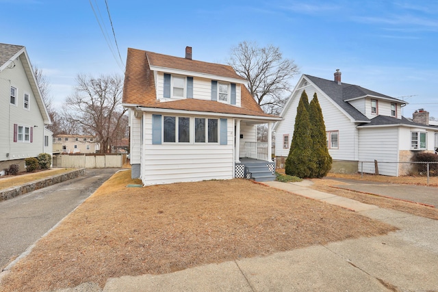 dutch colonial featuring driveway, roof with shingles, and fence