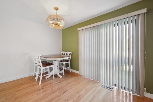 dining room featuring baseboards, wood finished floors, visible vents, and a notable chandelier