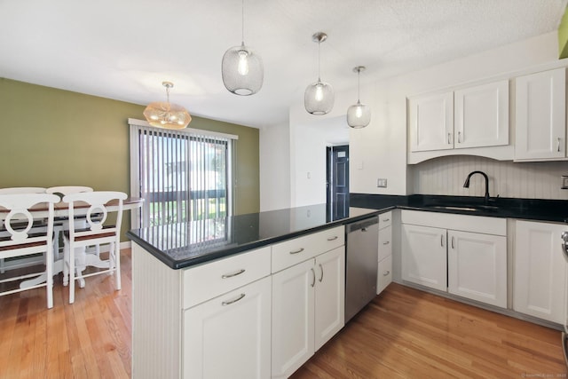 kitchen featuring light wood finished floors, a peninsula, a sink, white cabinetry, and stainless steel dishwasher