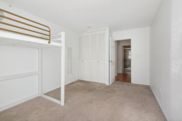 unfurnished bedroom with carpet, a closet, and a textured ceiling