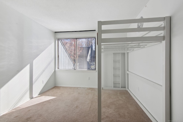 unfurnished bedroom with carpet floors, baseboards, and a textured ceiling