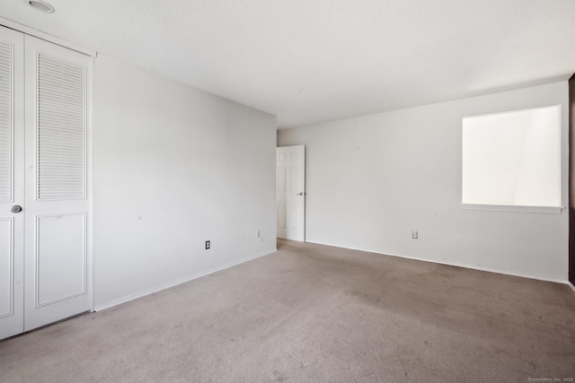 unfurnished room featuring light carpet and a textured ceiling