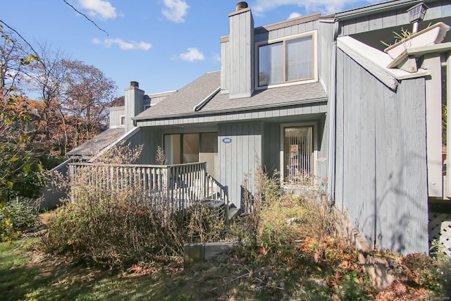 rear view of property with roof with shingles and a chimney