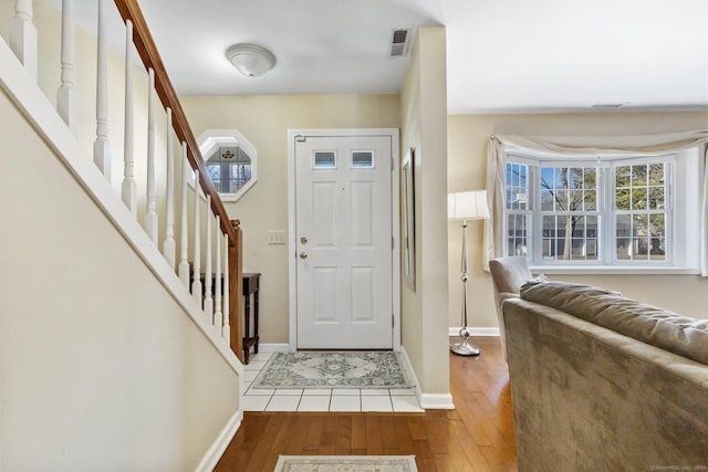 entrance foyer featuring visible vents, stairway, baseboards, and wood-type flooring