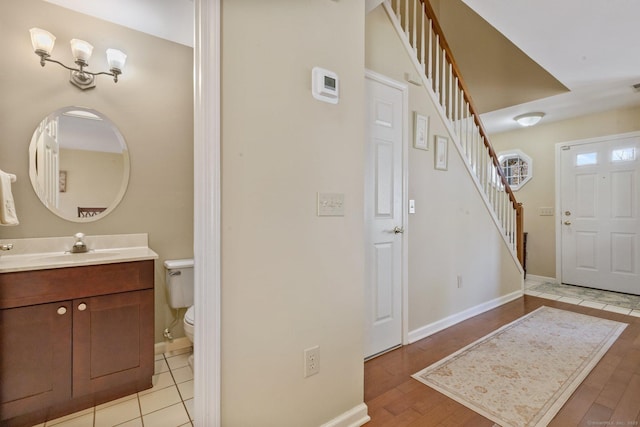 foyer entrance featuring stairs, baseboards, and light wood finished floors