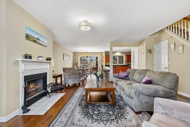 living area with a fireplace with flush hearth, stairway, baseboards, and wood finished floors