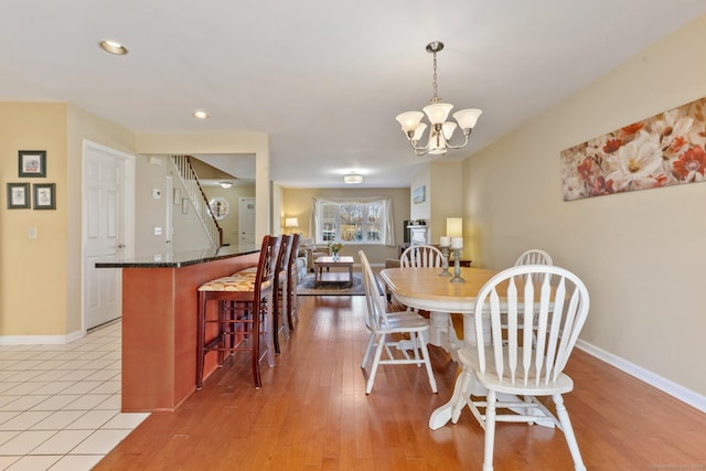 dining room with a notable chandelier, light wood-style floors, and baseboards