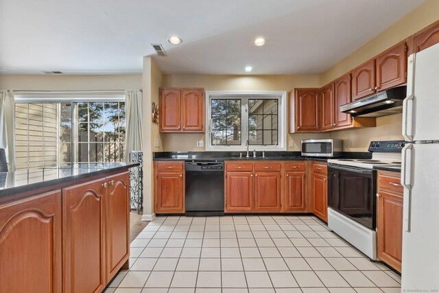 kitchen with white appliances, visible vents, a sink, under cabinet range hood, and dark countertops