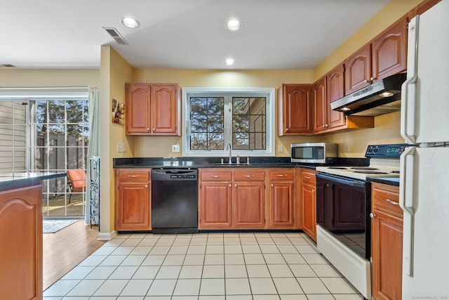 kitchen featuring visible vents, under cabinet range hood, a sink, dark countertops, and white appliances