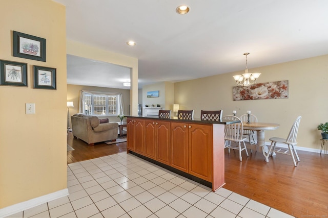 kitchen with light wood finished floors, open floor plan, brown cabinets, and an inviting chandelier