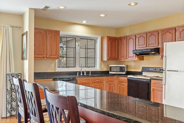 kitchen featuring visible vents, freestanding refrigerator, electric stove, under cabinet range hood, and stainless steel microwave