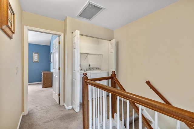 hallway featuring visible vents, baseboards, an upstairs landing, light colored carpet, and independent washer and dryer