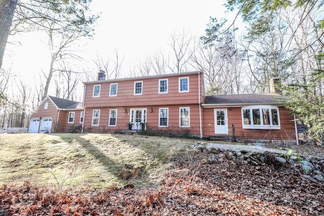 colonial-style house featuring a chimney and an attached garage