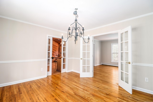 unfurnished dining area featuring french doors, crown molding, a baseboard heating unit, light wood-style floors, and baseboards