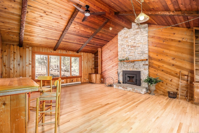 unfurnished living room with vaulted ceiling with beams, wood walls, a stone fireplace, and wood finished floors