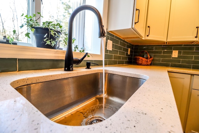 details featuring light stone counters, backsplash, and a sink