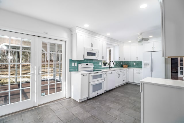 kitchen featuring white appliances, white cabinets, ceiling fan, light countertops, and backsplash