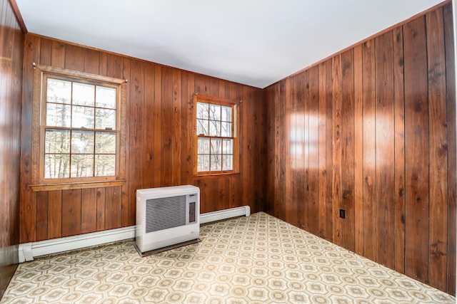 empty room with wood walls and a baseboard heating unit