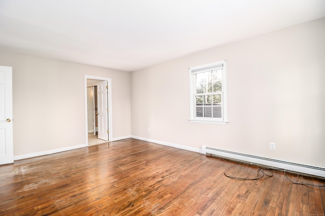 unfurnished room featuring a baseboard radiator, wood finished floors, and baseboards