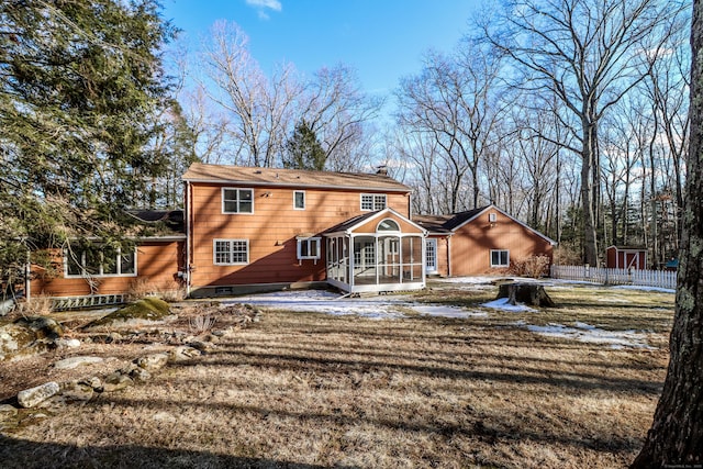 rear view of house featuring a chimney, fence, and a sunroom