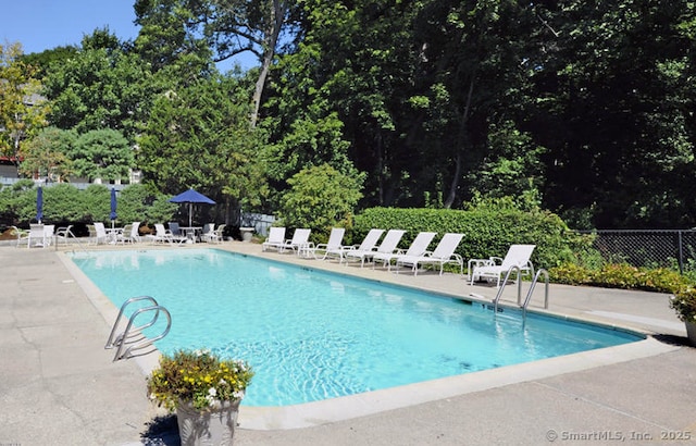 community pool with a patio and fence