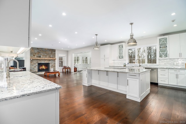 kitchen with stainless steel dishwasher, backsplash, dark wood finished floors, and white cabinets