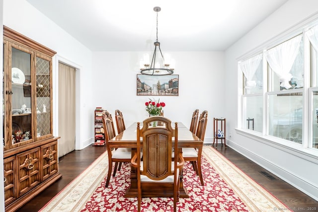 dining room with dark wood-type flooring, an inviting chandelier, visible vents, and baseboards